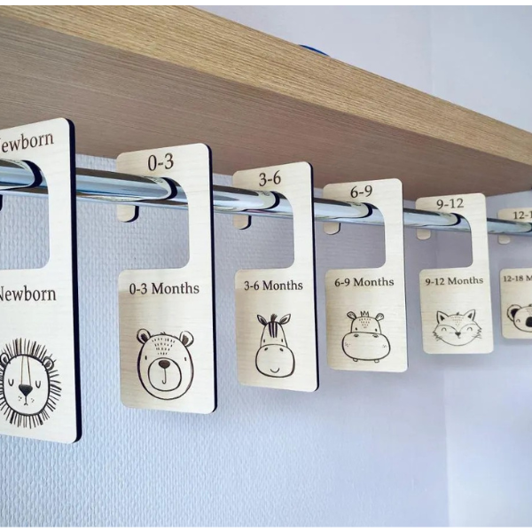 Clothing size labels with animal illustrations on a wooden shelf.