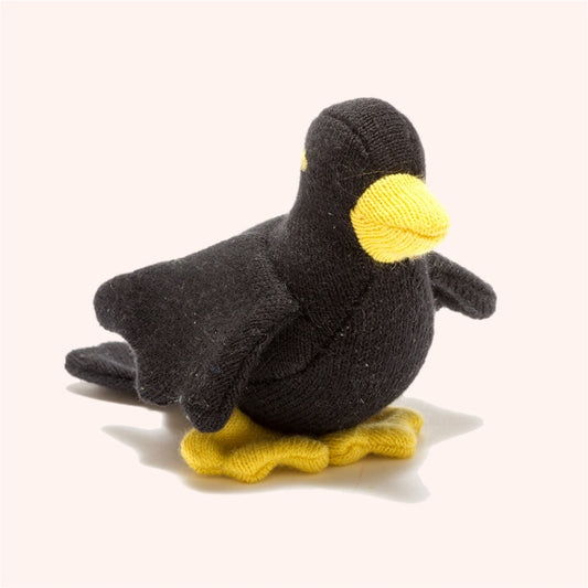 A small black organic cotton toy in the shape of a blackbird with yellow feet and a soft body, designed for sensory development.