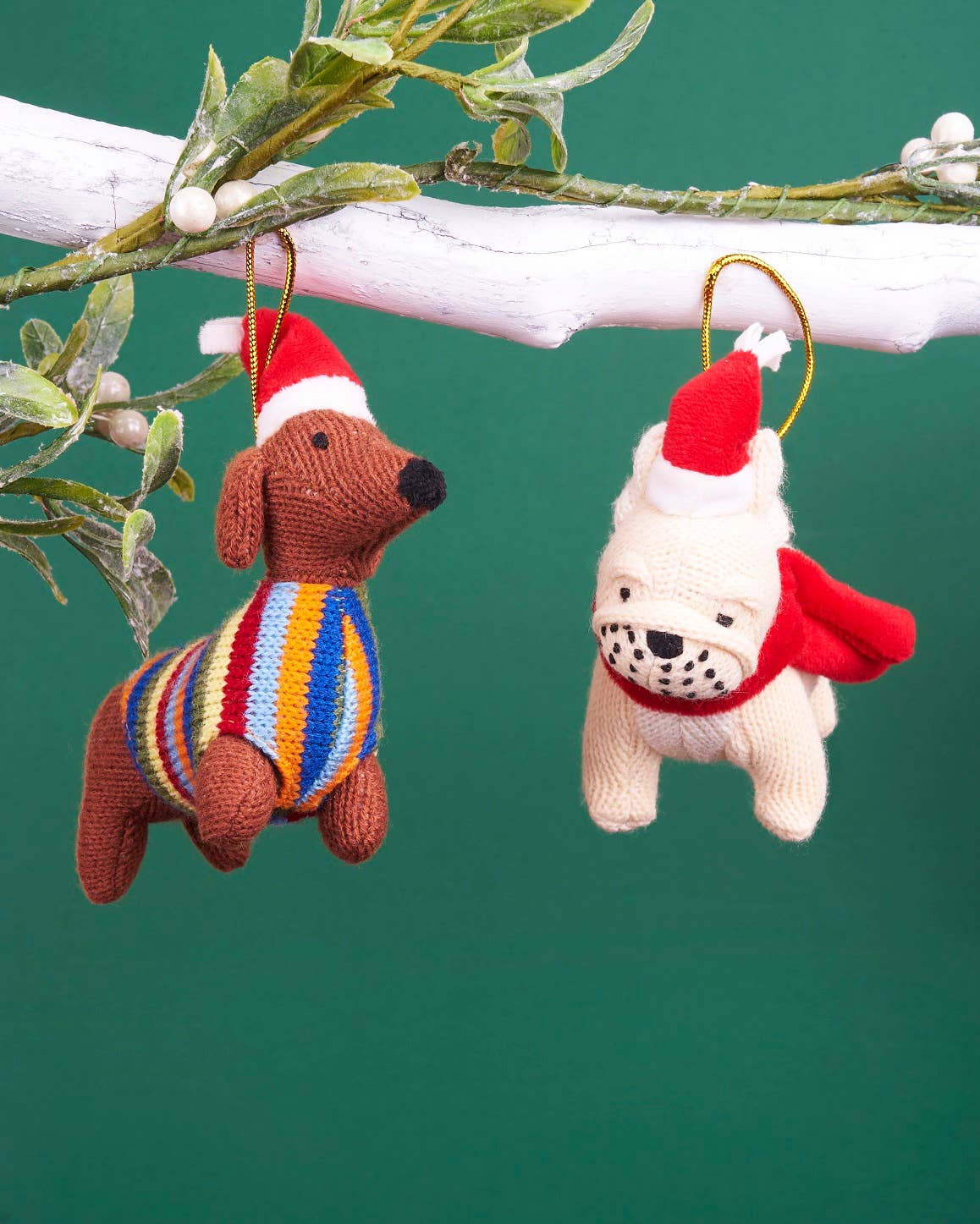 Knitted dog ornaments with Santa hats on a green background