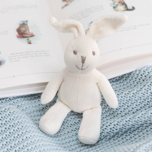 White plush bunny toy on a blue textured blanket with an open book in the background
