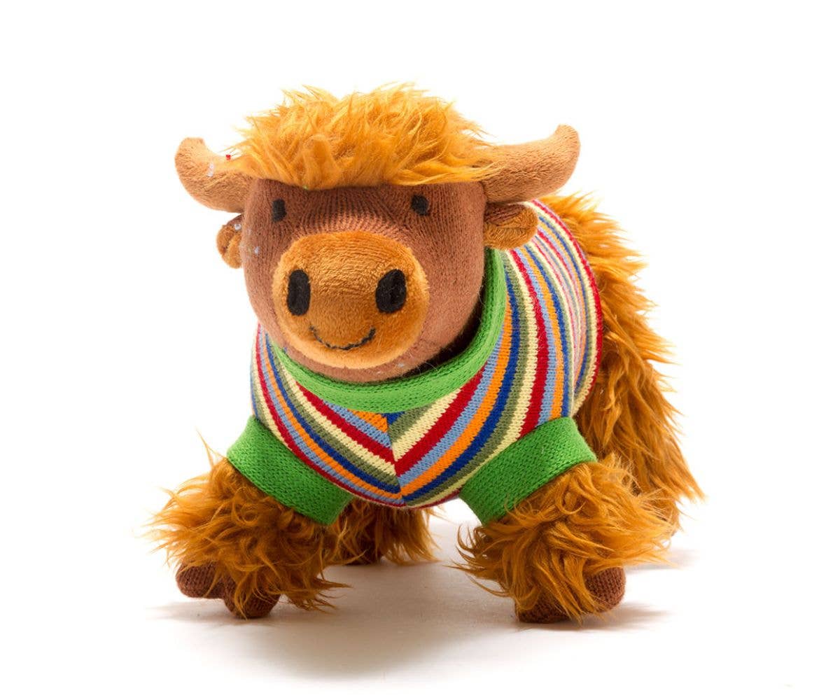 Plush toy cow wearing a colorful sweater on a white background