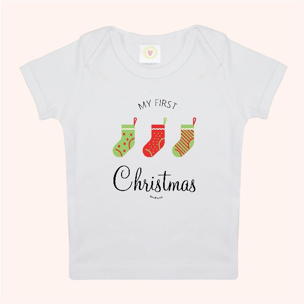 White baby t-shirt with 'My First Christmas' text and stockings on a white background