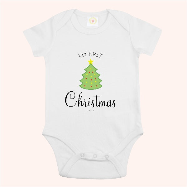 A white short-sleeve baby bodysuit with a graphic print of a green Christmas tree and the text 'MY FIRST Christmas' on a pale pink background.