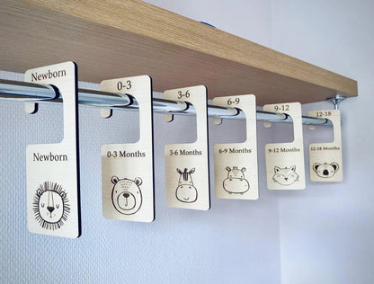 Clothing size labels with animal illustrations on a wooden shelf.